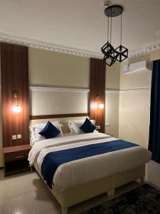 1 dormitorio con 1 cama grande con almohadas azules en المبيت 3 للشقق الفندقية en Abha