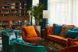 Hotel Indigo - Exeter, an IHG Hotel في إكسيتير: غرفة معيشة مع كراسي برتقالية وزرقاء وطاولة