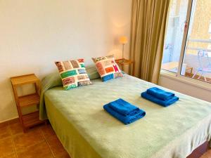 ein Schlafzimmer mit einem Bett mit blauen Kissen und einem Fenster in der Unterkunft Borinquen Sky Apartments in Playa de las Americas + 42 Fotos