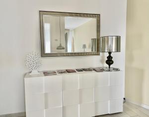um espelho numa parede por cima de uma cómoda branca em SunRise Apartments em Termoli