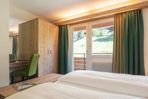 a bedroom with a bed and a desk and a window at Hotel Restaurant Alpina in Grindelwald