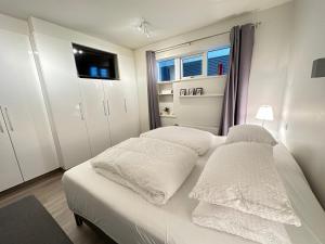 a bed with white sheets and pillows in a room at Modern 2 bedroom apartment in Kópavogur in Reykjavík