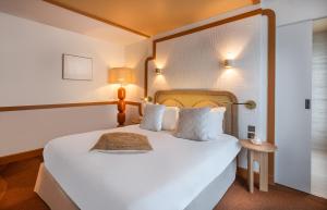 a bedroom with a large white bed and a lamp at Hôtel Le Monna Lisa by Inwood Hotels in Paris