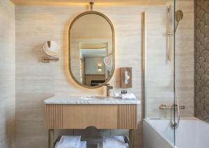 La salle de bains est pourvue d'un lavabo, d'un miroir et d'une baignoire. dans l'établissement Hôtel Le Monna Lisa by Inwood Hotels, à Paris
