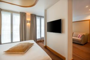パリにあるHôtel Le Monna Lisa by Inwood Hotelsのベッド1台、薄型テレビが備わるホテルルームです。