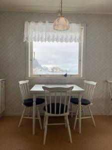 a table and chairs in a room with a window at House by the sea Reine, Lofoten in Reine