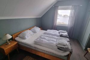 a bed with white sheets and a window in a bedroom at House by the sea Reine, Lofoten in Reine