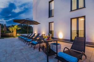 un patio con sedie e un tavolo con un ombrellone di Villa Ivani a Sukošan (San Cassiano)