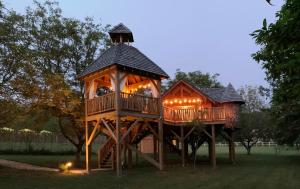 une cabane dans les arbres avec des lumières sur l'herbe dans l'établissement Domaine de Campagnac - Spa & Sauna, à Carsac-Aillac