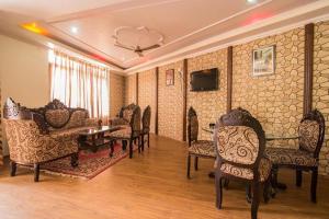 a waiting room with chairs and a table and a tv at Hotel Moon by Excellent Hospitality in Nainital