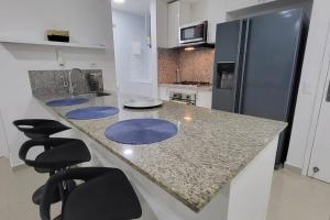 eine Küche mit einer Theke mit Hockern und einem Kühlschrank in der Unterkunft LUJOSO Apartamento en Cartagena Incluye Servicio Domestico in Cartagena de Indias