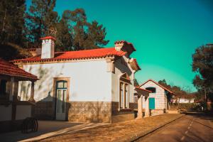 une maison blanche avec un toit rouge dans une rue dans l'établissement Estação Ferroviária de Lourido, à Castelbuono