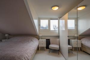 ein Schlafzimmer mit einem Bett und einem Stuhl sowie zwei Fenstern in der Unterkunft Meerzicht 99 - Luxury house 30 minutes from Amsterdam in Uitgeest