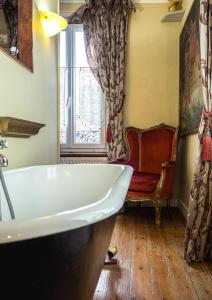 een badkamer met een bad, een stoel en een raam bij Chambres d'hôtes Villa l'espérance in Étretat
