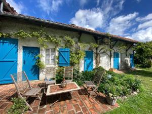 una casa con puertas azules y sillas en un patio de ladrillo en Domaine Du Tafiart, en Sarron