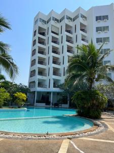 un hôtel avec une piscine en face d'un bâtiment dans l'établissement sea sand sun resort Executive Mae Rumphueng beach, à Rayong
