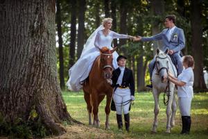 uma noiva e um noivo montados num cavalo com uma família em Jumpravas pils em Jumprava