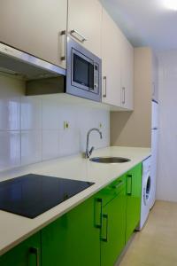 cocina con armarios verdes y microondas en Playa Home Helgueras con acceso a Spa (AguaMarinaSpa) en Noja