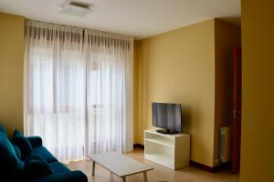 uma sala de estar com um sofá azul e uma televisão em Playa Home Helgueras con acceso a Spa (AguaMarinaSpa) em Noja