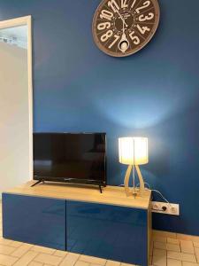 un televisor en una pared azul con un reloj en Le Saint-Amour appartement classé 2 étoiles, en Saint-Amour