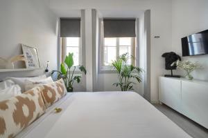 - une chambre blanche avec un grand lit blanc orné de plantes dans l'établissement Lisboa nova Central - bica 2E, à Lisbonne