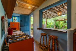 een keuken met een oranje fornuis en krukken bij Casa PROX AO MAR - Icaraizinho de Amontada in Amontada