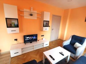 sala de estar con TV y silla azul en Апартамент за нощувка, център!, en Stara Zagora