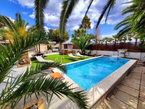 een zwembad in een achtertuin met palmbomen bij Villa Tore in Quartu SantʼElena