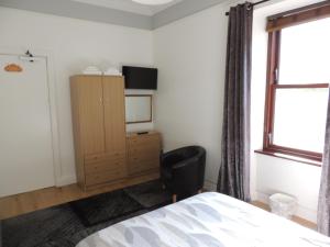 1 dormitorio con cama, escritorio y ventana en 5A Union Road en Macduff