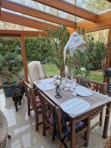 Una mesa de madera con sillas y un perro en un patio. en Siedem C, en Pobierowo