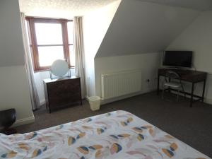 1 dormitorio con cama, escritorio y ventana en 5A Union Road en Macduff