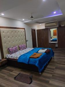 um quarto com uma cama grande com lençóis azuis e almofadas roxas em Mahathi Residency 