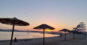 a group of umbrellas on a beach at sunset at Apartment David in Biograd na Moru