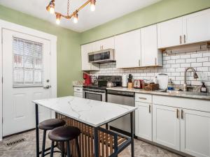 a kitchen with white cabinets and a table with stools at Blenkner Bungalowgvillagepetsok in Columbus