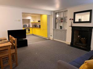 a living room with a fireplace and a yellow kitchen at Entire 2-bedroom Flat in Camden in London