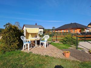 Garz的住宿－Ferienwohnung Riemer，庭院设有两把椅子和一张桌子,还有一间狗屋。
