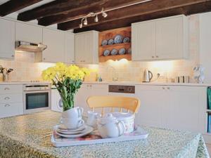 una cocina con una mesa con un jarrón de flores. en Shamrock Cottage en Cenarth