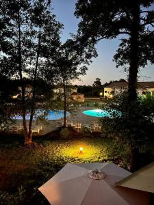 stół z parasolem przed basenem w obiekcie Appartement piscine 500m de la plage vue montagne w mieście Moriani-Plage