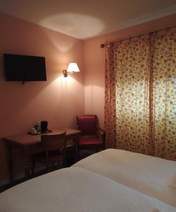 a hotel room with a bed and a table and a television at Logis Auberge le centre poitou in Coulombiers