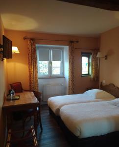 a hotel room with two beds and a table and window at Logis Auberge le centre poitou in Coulombiers