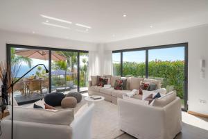 a living room with white furniture and large windows at Villa Hibiscus by An Island Apart in Calheta