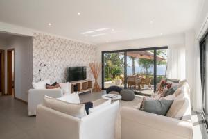a living room with white couches and a television at Villa Hibiscus by An Island Apart in Calheta