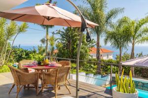 stół i krzesła z parasolem na patio w obiekcie Villa Hibiscus by An Island Apart w mieście Calheta