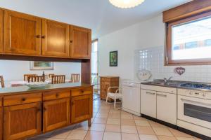 una cucina con armadietti in legno ed elettrodomestici bianchi di Casa Agnese, Levico Terme - Ospitar a Levico Terme