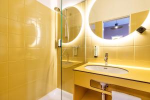 Baño amarillo con lavabo y espejo en Kloster by b-smart, en Schaan