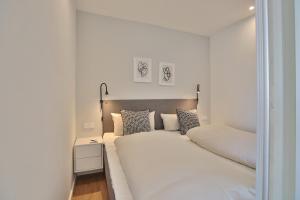 ein weißes Schlafzimmer mit einem großen weißen Bett mit Kissen in der Unterkunft Residenz am Hang Residenz am Hang Appartement 311 in Scharbeutz