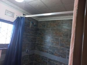 a bathroom with a shower with a blue shower curtain at Sweetwaters Guest House in Estcourt