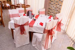 una mesa con sillas blancas con arcos rojos en MS Hotel, en Dobra Voda