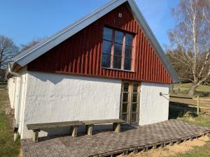 einem rot-weißen Gebäude mit einer Bank davor in der Unterkunft Navröds Gård in Sjöbo