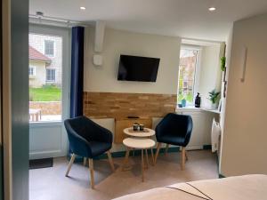 a room with two chairs and a table and a tv at Au fil de l’Ô in Bisseuil